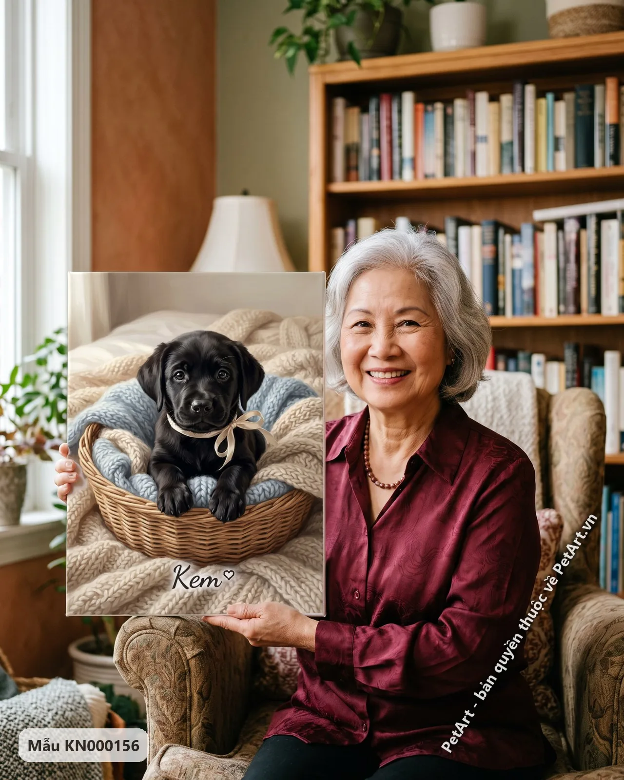 Ảnh thực tế: Chú chó Labrador đen con lông mượt, đeo nơ kem, ngồi trong giỏ mây lót chăn len xanh và kem.