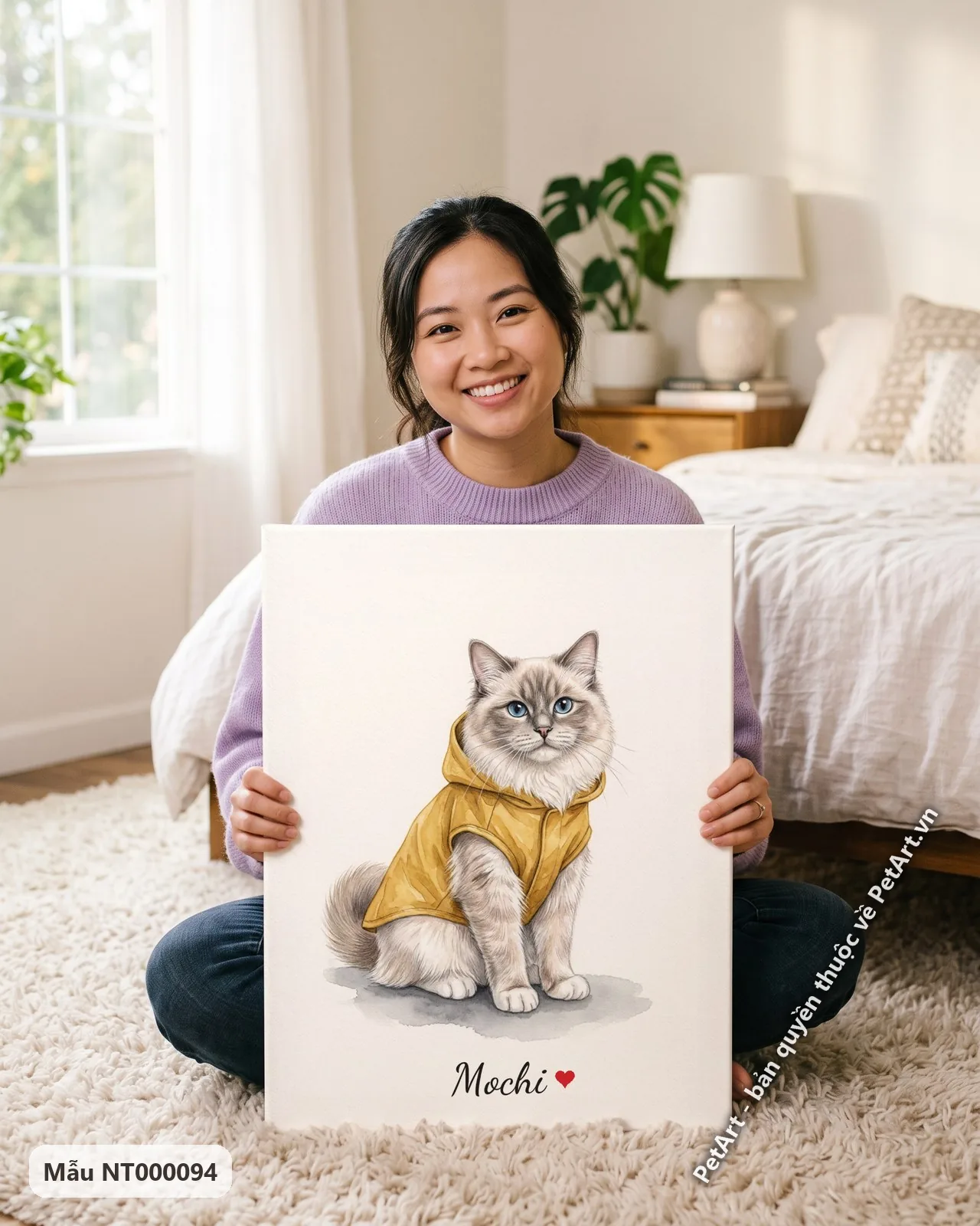 Ảnh thực tế: Một chú mèo Ragdoll lông trắng xám mắt xanh đang ngồi, mặc áo khoác có mũ màu vàng tươi trên nền trắng.